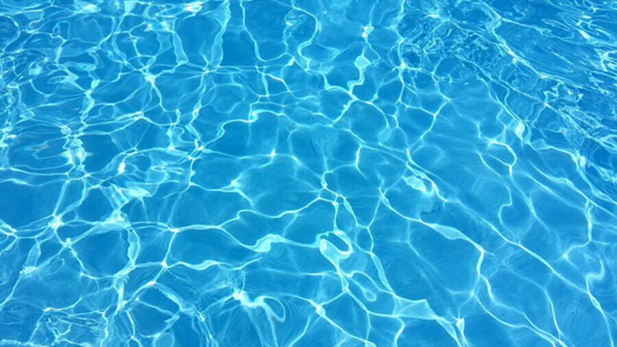 Up close view of shimmery bright blue water in a swimming pool.